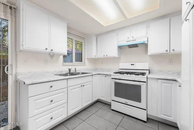 a kitchen with granite countertop white cabinets and white appliances