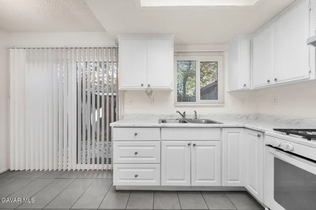 a kitchen with granite countertop white cabinets and window