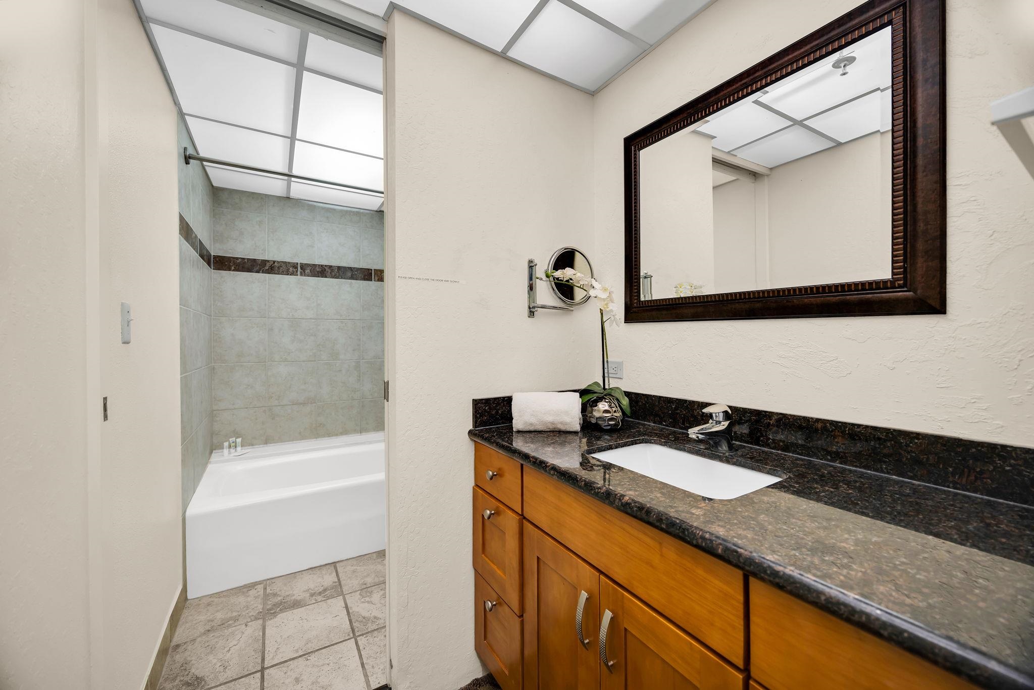 3445 Lower Honoapiilani Road, Unit 516 Lahaina, HI 96761 - Photo 27 of 49 a bathroom with a granite countertop sink a mirror and a bathtub