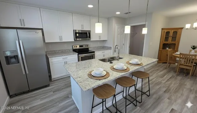 a kitchen with stainless steel appliances granite countertop a dining table chairs refrigerator and microwave