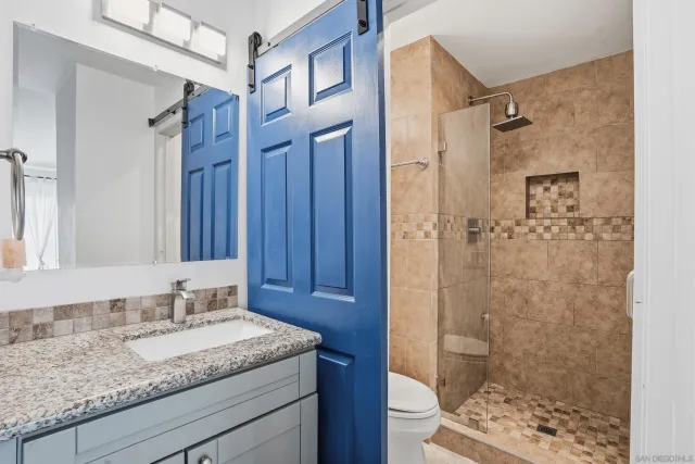 a bathroom with a granite countertop sink a mirror and shower