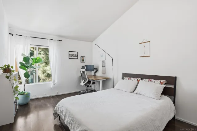 a large bed sitting in a bedroom next to a window and a wooden floor