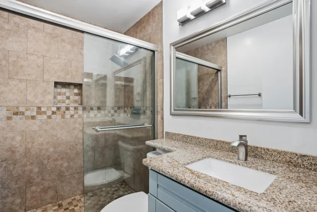 a bathroom with a granite countertop sink toilet and shower
