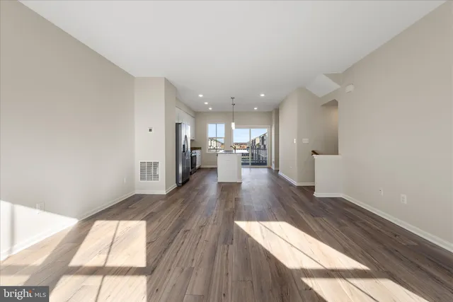 a kitchen with kitchen island granite countertop a refrigerator oven a sink and white cabinets with wooden floor