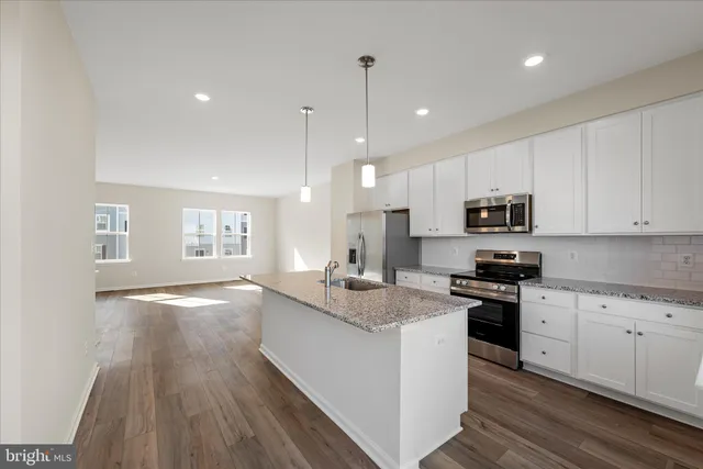 a kitchen with stainless steel appliances granite countertop a sink a stove and a wooden cabinets