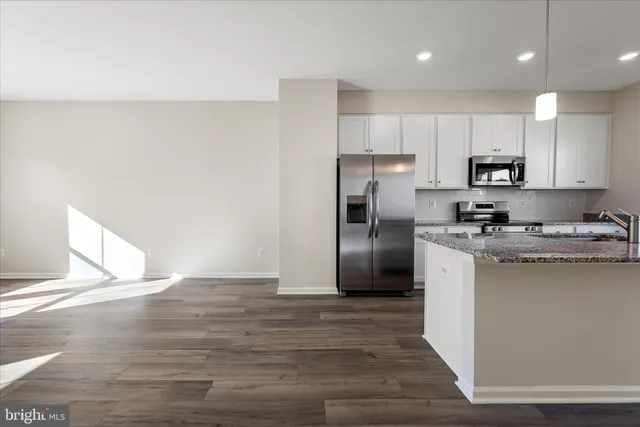 a kitchen with granite countertop a refrigerator and a stove top oven