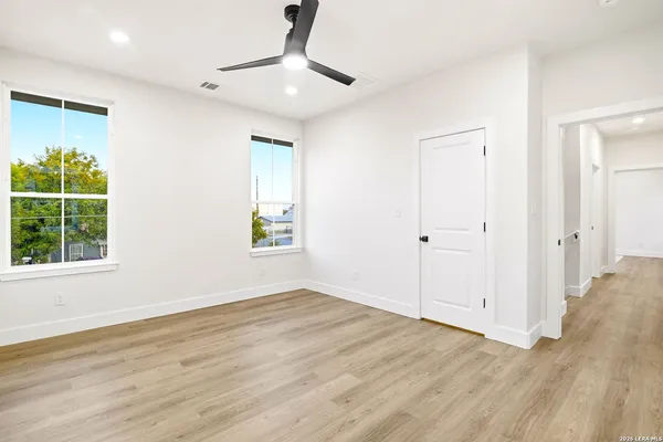 an empty room with wooden floor fan and windows