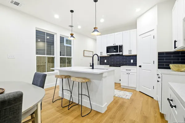a kitchen that has a lot of white cabinets and stainless steel appliances