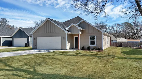 a house that has a big yard large trees with wooden fence