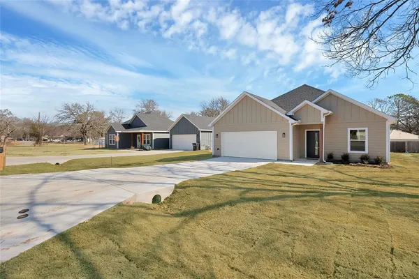 a view of a house with a yard and large tree