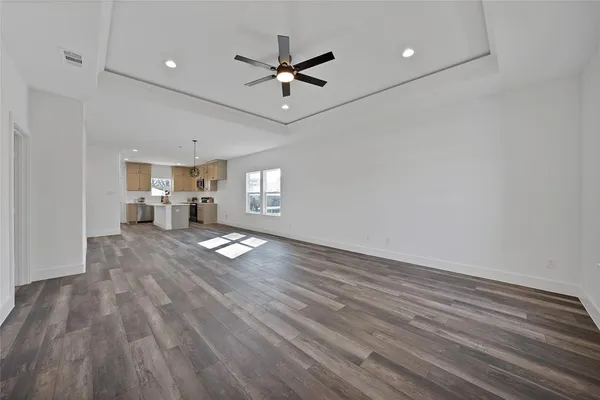 a view of empty room with wooden floor and fan