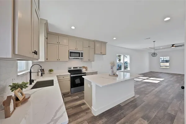 a kitchen with granite countertop a sink stainless steel appliances and white cabinets