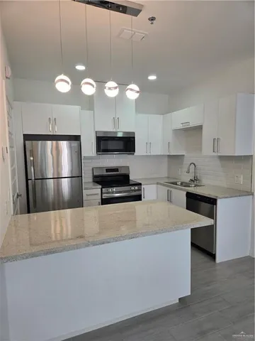 a large kitchen with stainless steel appliances a large counter top a stove and a refrigerator