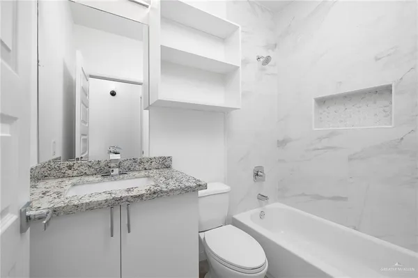 a bathroom with a granite countertop sink toilet and shower