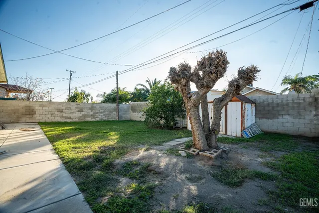 a view of a house with a small yard and a large tree