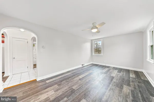 an empty room with wooden floor chandelier fan and windows