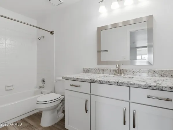 a bathroom with a granite countertop toilet sink and mirror