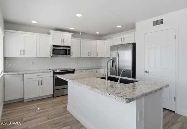 a kitchen with kitchen island granite countertop a stove sink and microwave