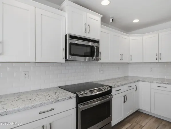 a kitchen with granite countertop white cabinets and stainless steel appliances