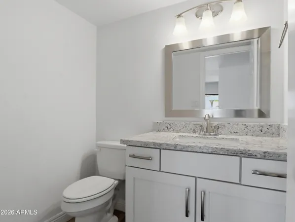 a bathroom with a granite countertop toilet sink mirror and vanity