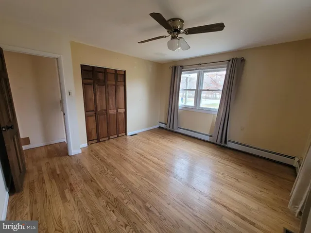 a view of empty room with wooden floor and fan