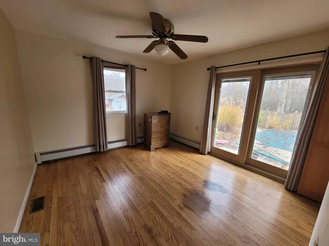 a view of an empty room with a window and wooden floor