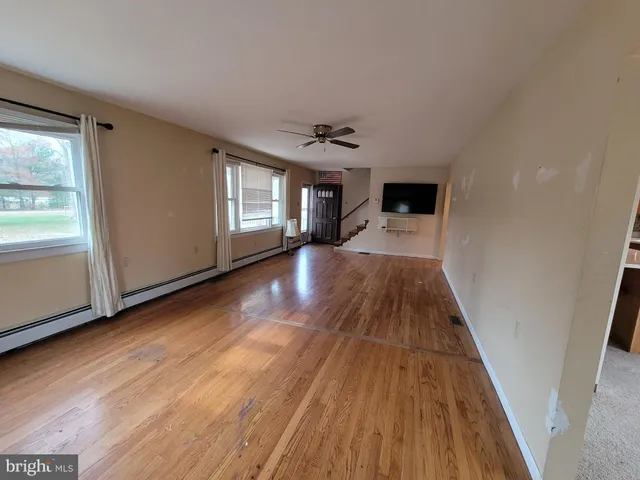 a view of a hallway with wooden floor and a living room