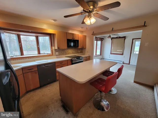 a kitchen with a stove a sink dishwasher a dining table and chairs with wooden floor