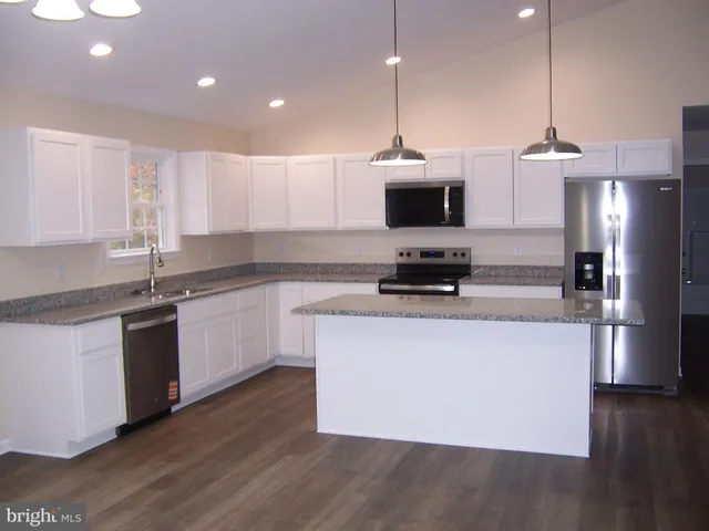 a kitchen with stainless steel appliances granite countertop a sink a stove and a granite counter top
