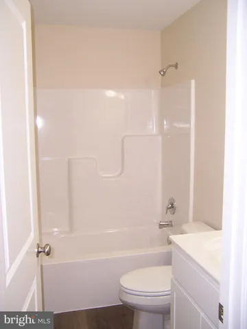 a bathroom with a granite countertop bathtub shower sink vanity and toilet