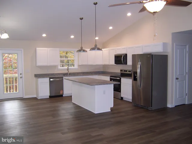 a large kitchen with stainless steel appliances granite countertop a stove a sink dishwasher a microwave oven and a refrigerator with wooden floor