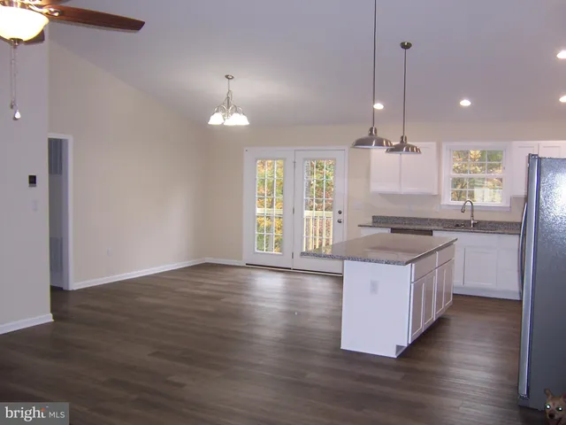 an open kitchen with granite countertop wooden floor a refrigerator and a sink