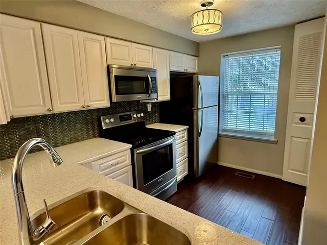 a kitchen with stainless steel appliances granite countertop a stove a sink and a microwave