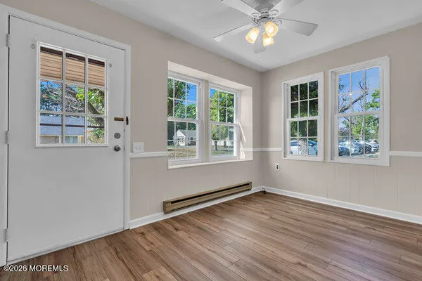 a view of an empty room with wooden floor and a window