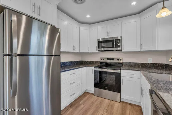 a kitchen with granite countertop a refrigerator stove and microwave