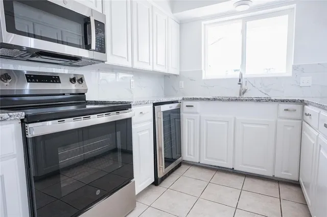 a kitchen with granite countertop white cabinets stainless steel appliances and a sink