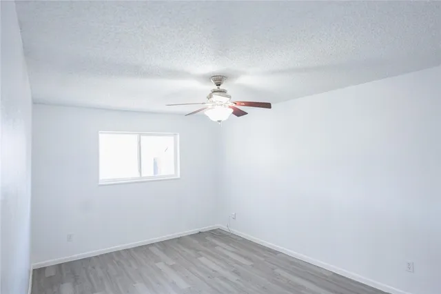an empty room with a window and ceiling fan