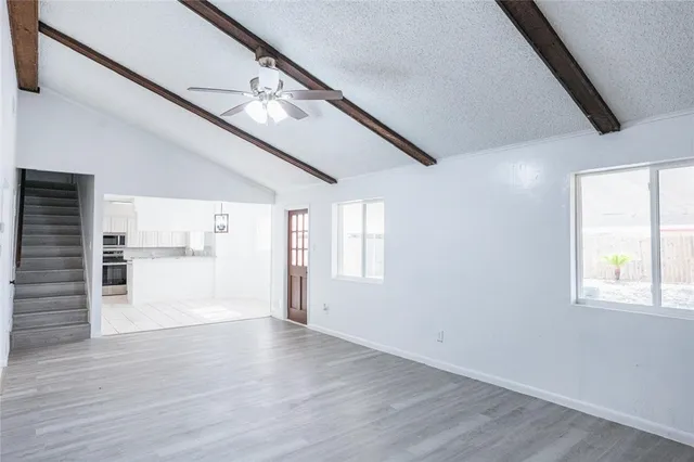 a view of empty room with wooden floor and fan