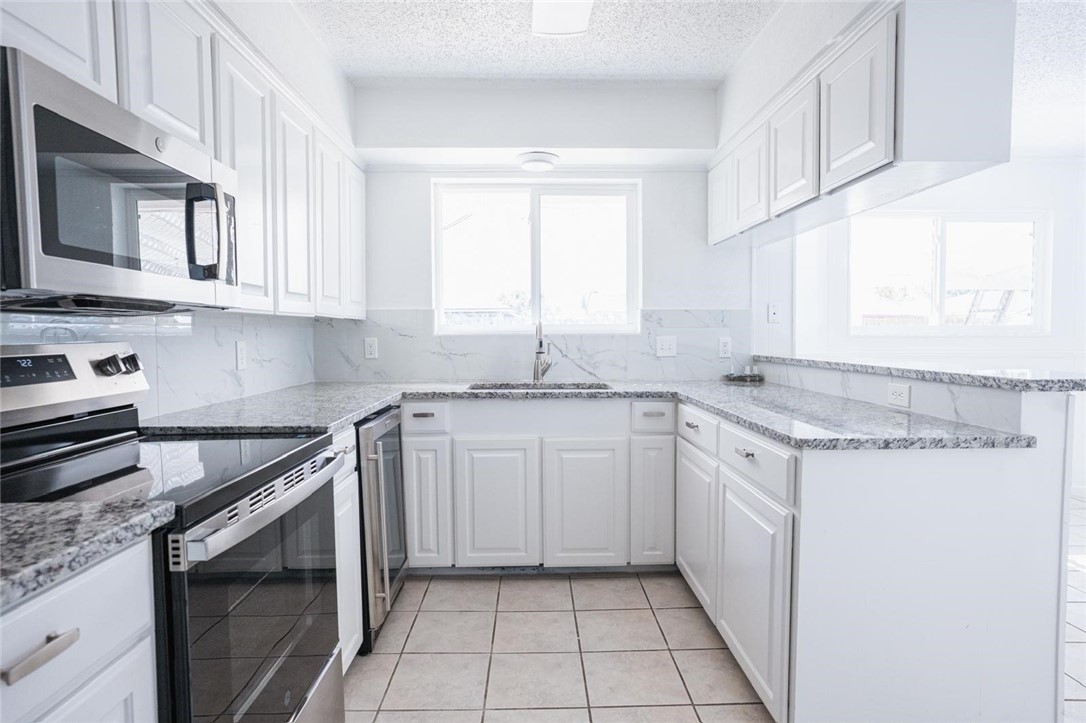 4509 Hogan Street Corpus Christi, TX 78413 - Photo 10 of 27 a kitchen with granite countertop white cabinets stainless steel appliances a sink and a window