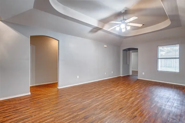 a view of an empty room with wooden floor and a chandelier