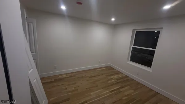 a view of an empty room with wooden floor and stairs