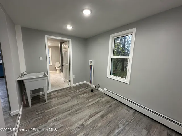 an empty room with wooden floor and fan