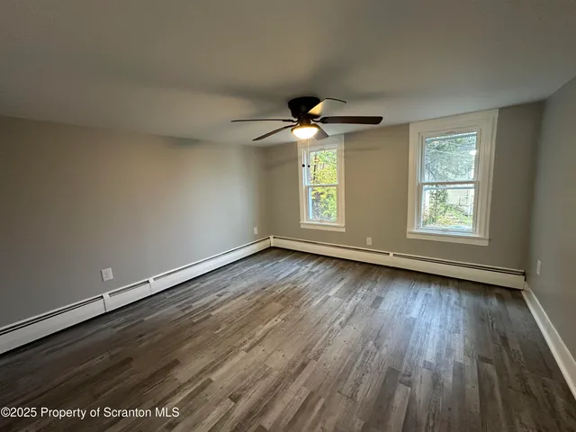 an empty room with wooden floor chandelier and windows
