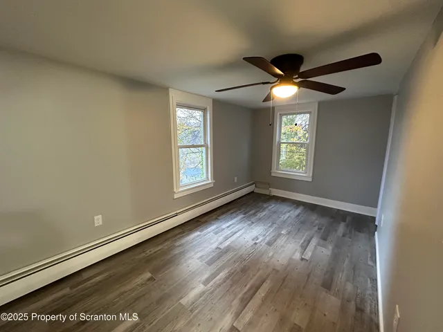 an empty room with wooden floor and fan