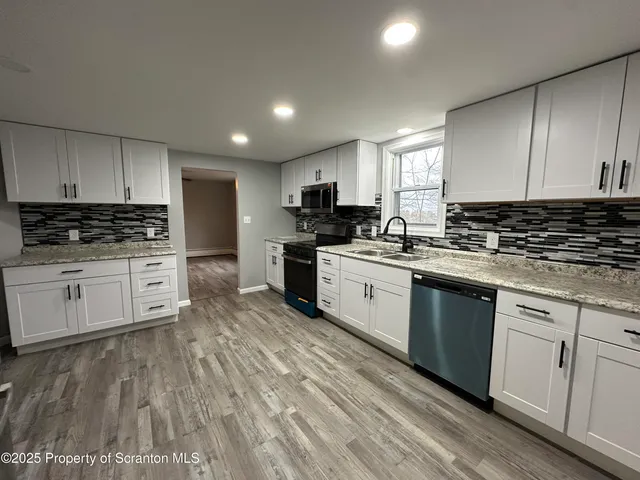 a kitchen with granite countertop a sink a counter top space stainless steel appliances and cabinets