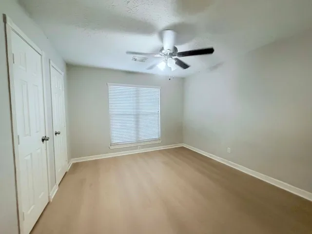 a backyard of a house with plants and large tree