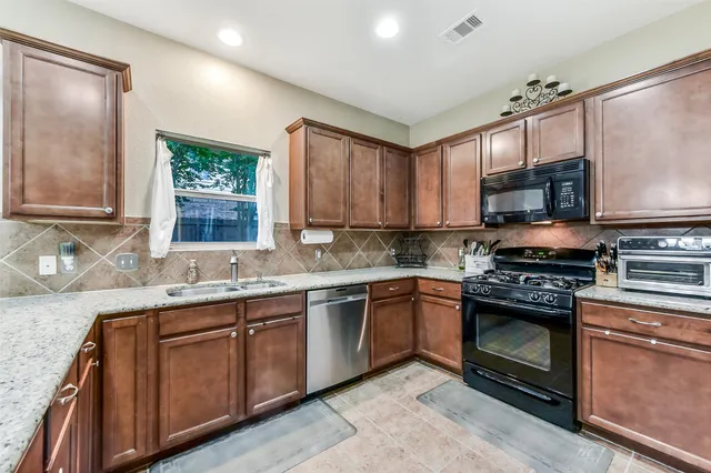 a kitchen with stainless steel appliances granite countertop a stove a sink and a microwave