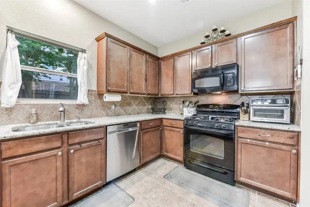 a kitchen with stainless steel appliances granite countertop a stove a sink and a microwave