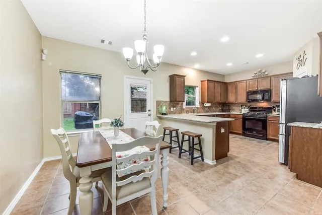 a open kitchen with stainless steel appliances granite countertop a stove a refrigerator a kitchen island a dining table and chairs