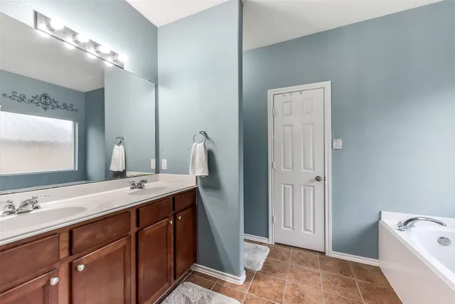 a spacious bathroom with a double vanity sink a mirror and a bathtub